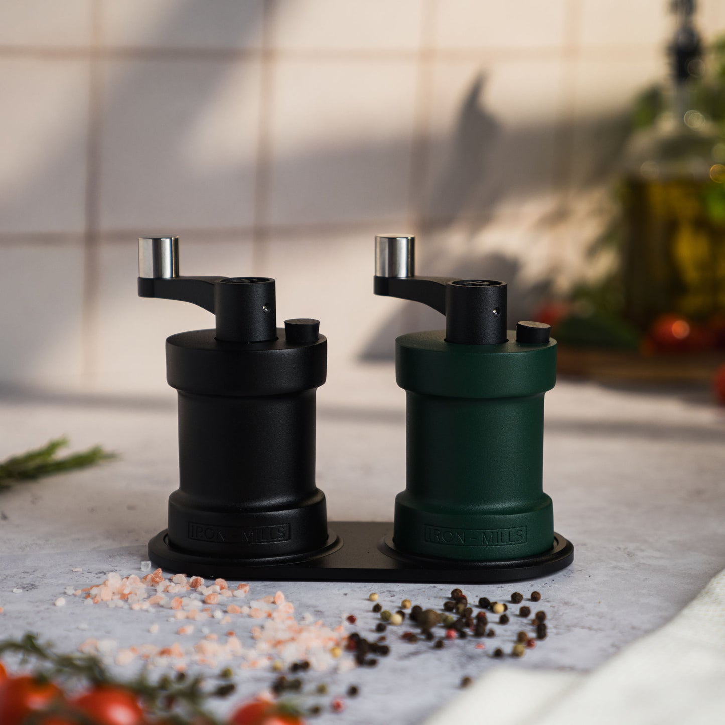 Iron-Mills onyx black and ivy green salt and pepper mills displayed on a durable mill rest in a rustic kitchen environment