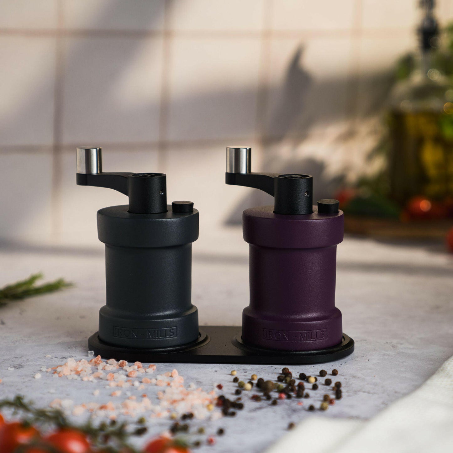 Iron-Mills anthracite grey and purple salt and pepper mills resting on a durable aluminium base in a stylish kitchen
