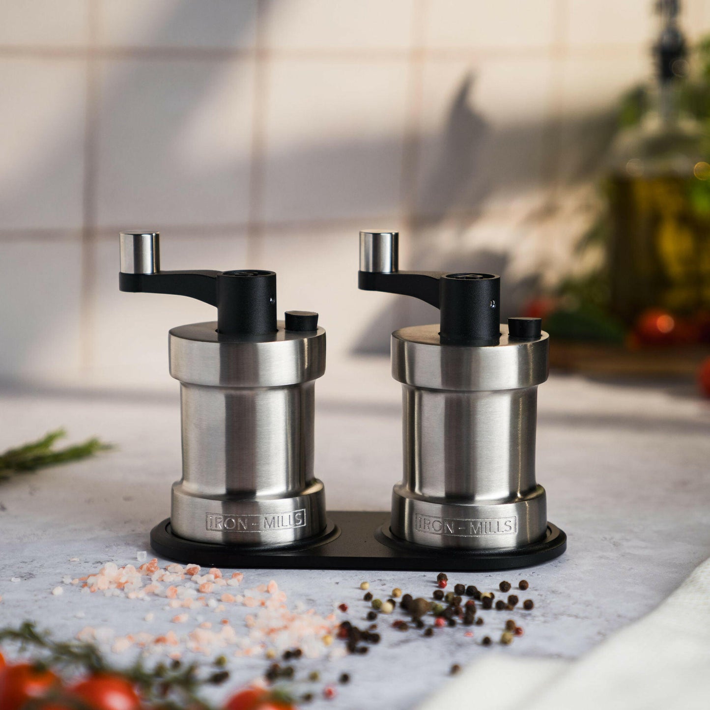 Iron-Mills brushed stainless steel salt and pepper mills displayed on a rest showcasing their timeless design