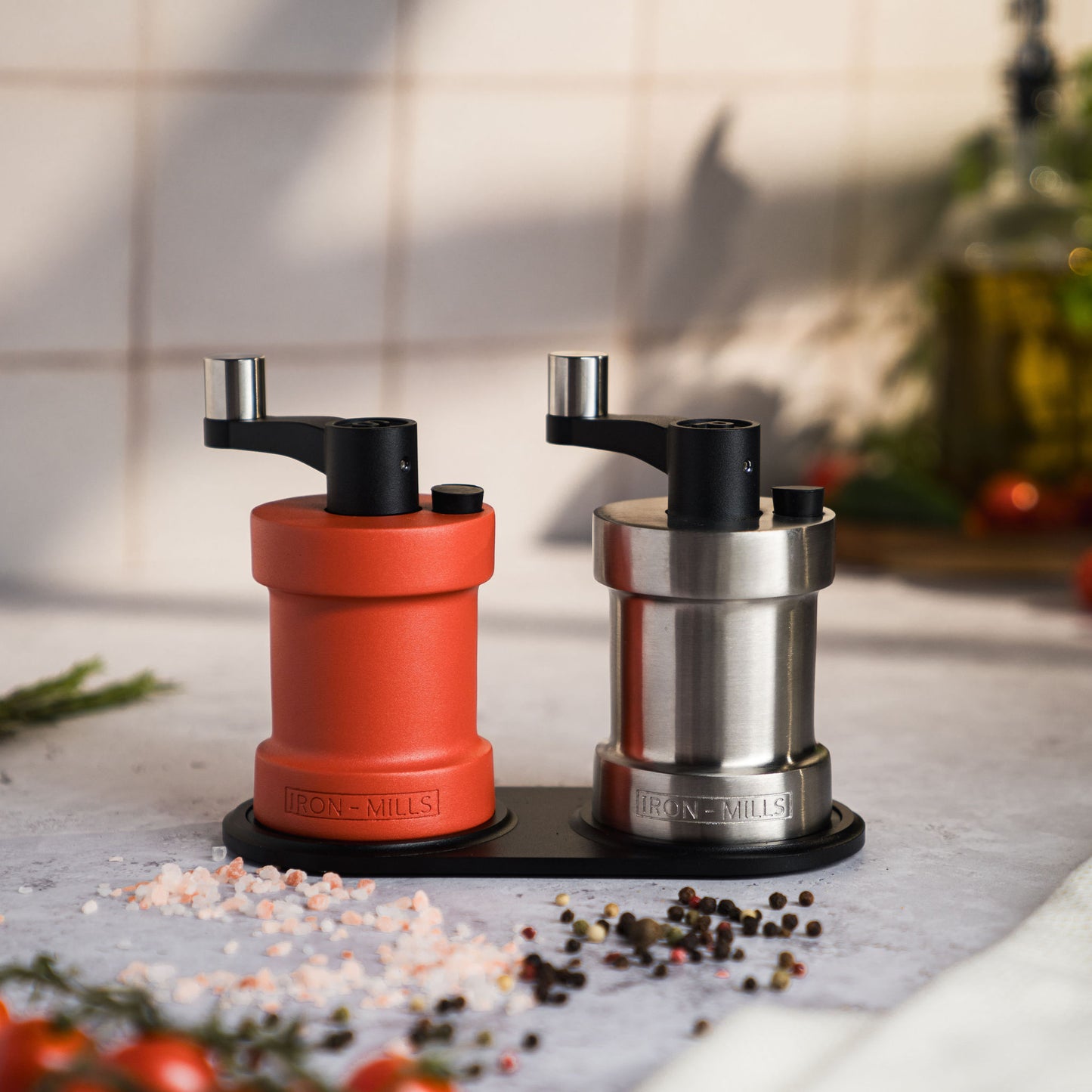 Iron-Mills coral red and brushed stainless steel salt and pepper mills on a high-quality mill base for a premium display