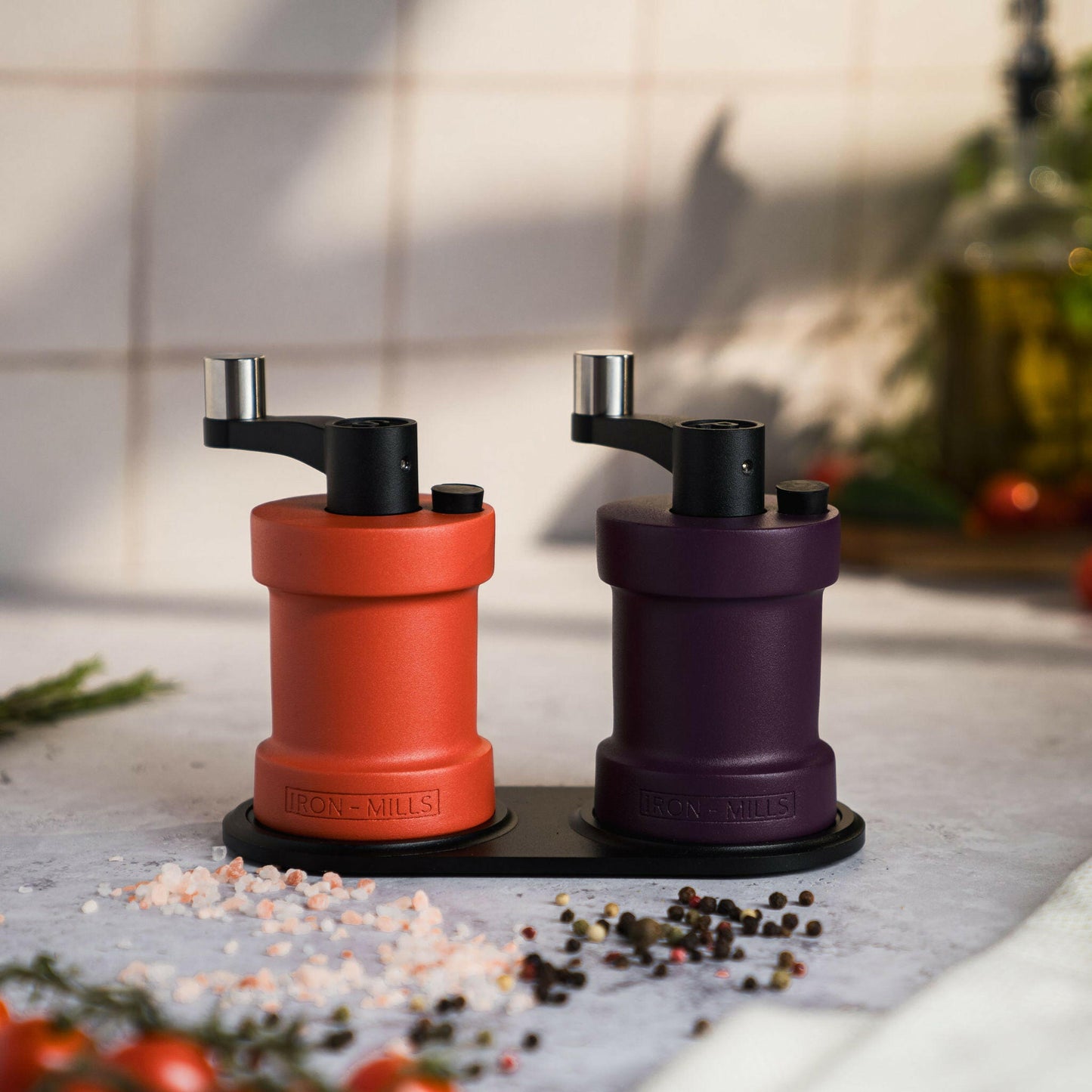 Iron-Mills coral red and deep purple salt and pepper mills displayed on a premium mill rest for a vibrant colour pairing