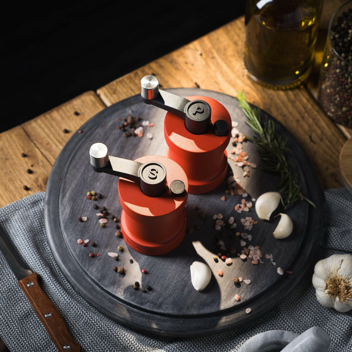 Iron-Mills coral red salt and pepper mills on a chopping board in a bright kitchen with condiments