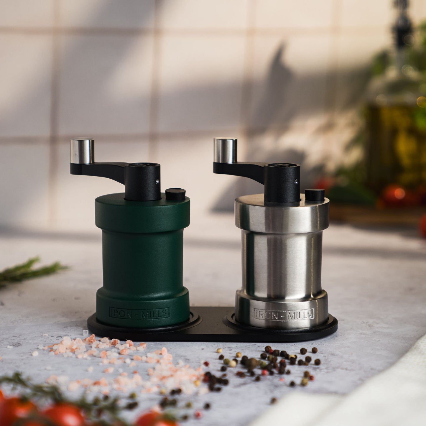 Iron-Mills ivy green and brushed stainless steel salt and pepper mills resting on a handcrafted wooden base for elegance