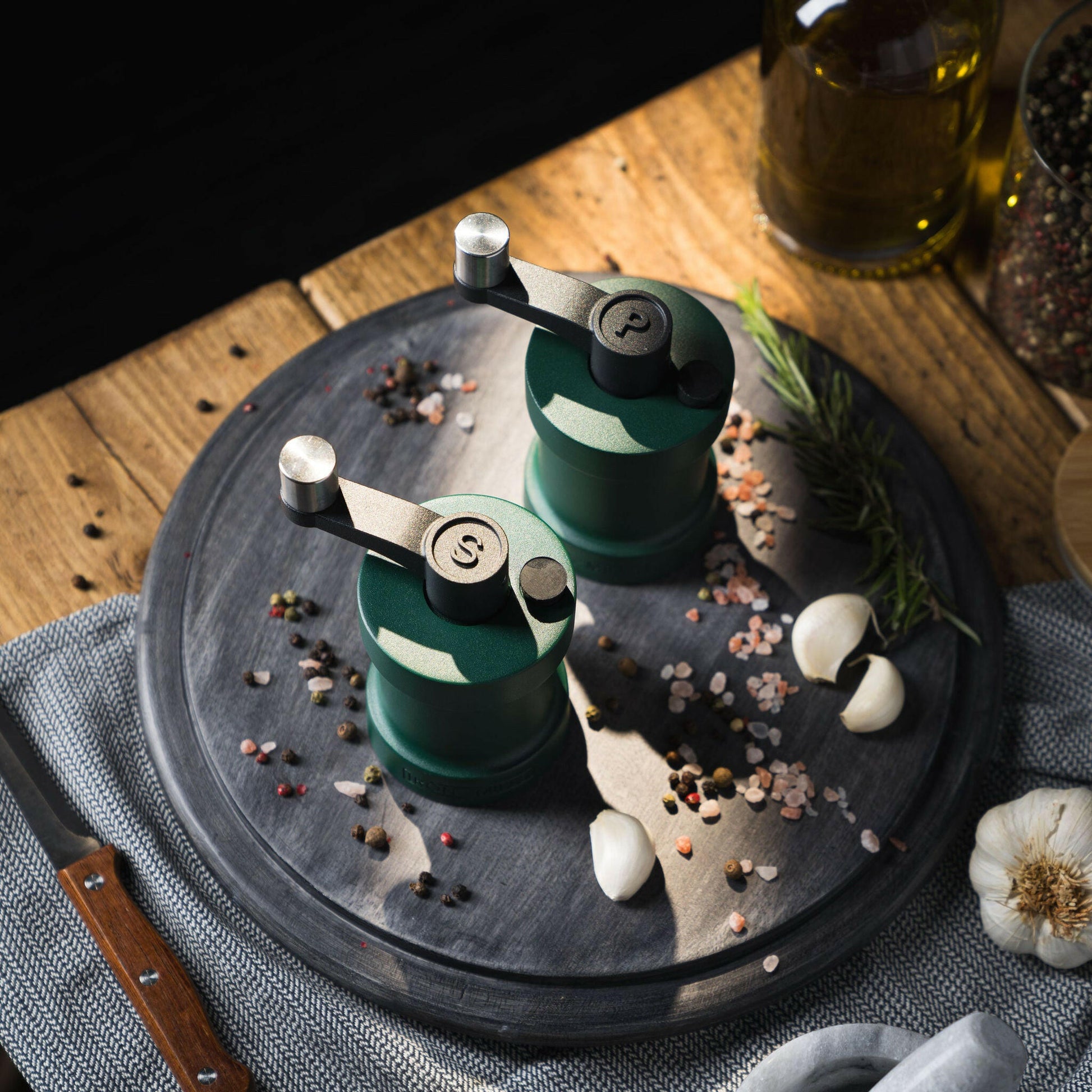 Iron-Mills ivy green salt and pepper mills on a chopping board in a stylish kitchen with condiments