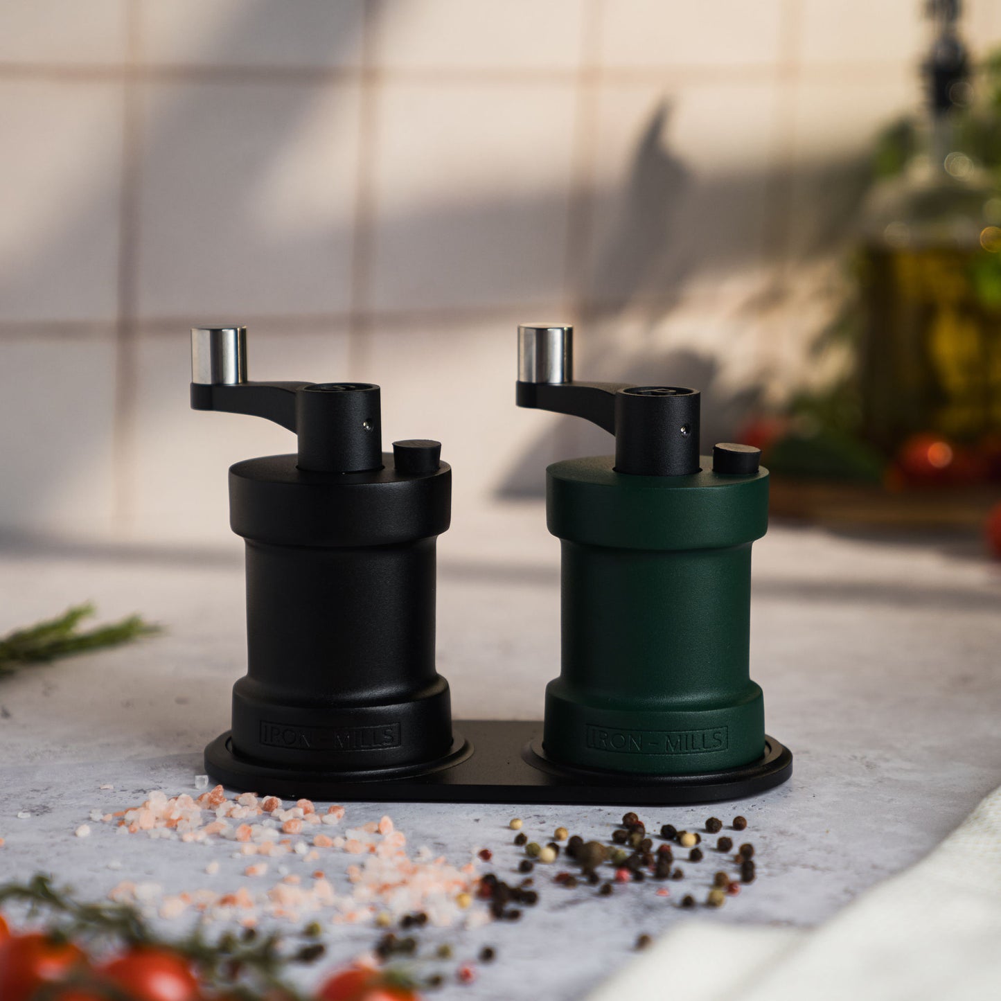 Iron-Mills onyx black and ivy green salt and pepper mills displayed on a durable mill rest in a rustic kitchen environment
