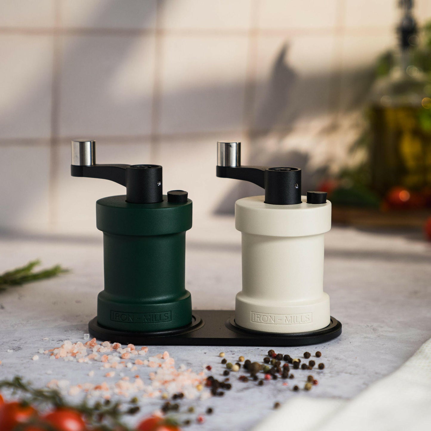 Iron-Mills oyster white and ivy green salt and pepper mills set on a cast aluminium mill rest, perfect for a modern kitchen aesthetic
