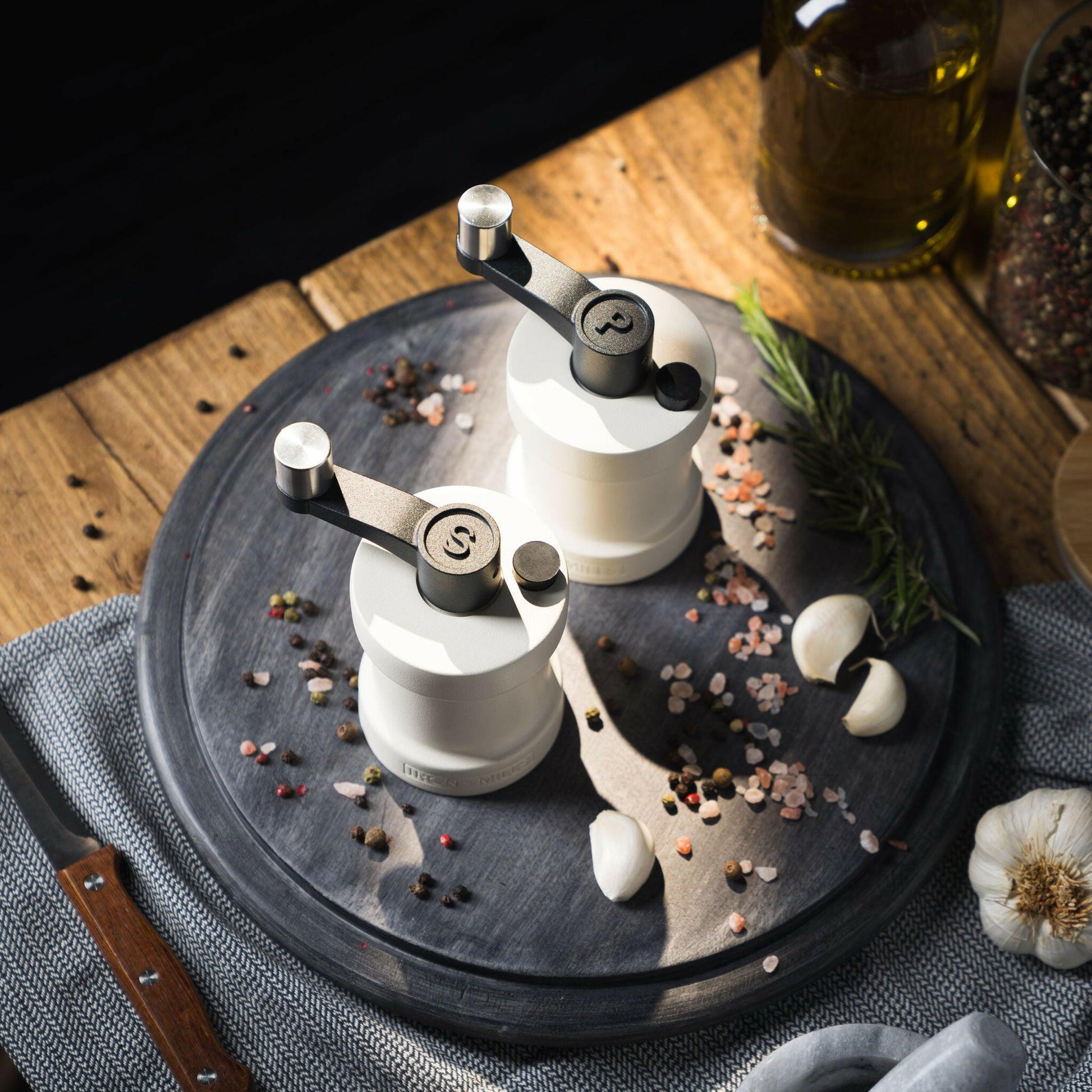 Iron-Mills oyster white salt and pepper mills on a chopping board in a kitchen surrounded by spices