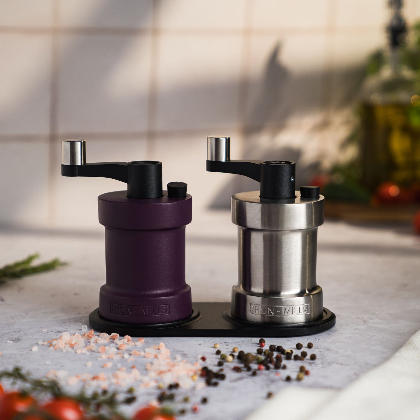 Iron-Mills deep purple and brushed stainless steel salt and pepper mills displayed on a mill rest for a luxurious pairing