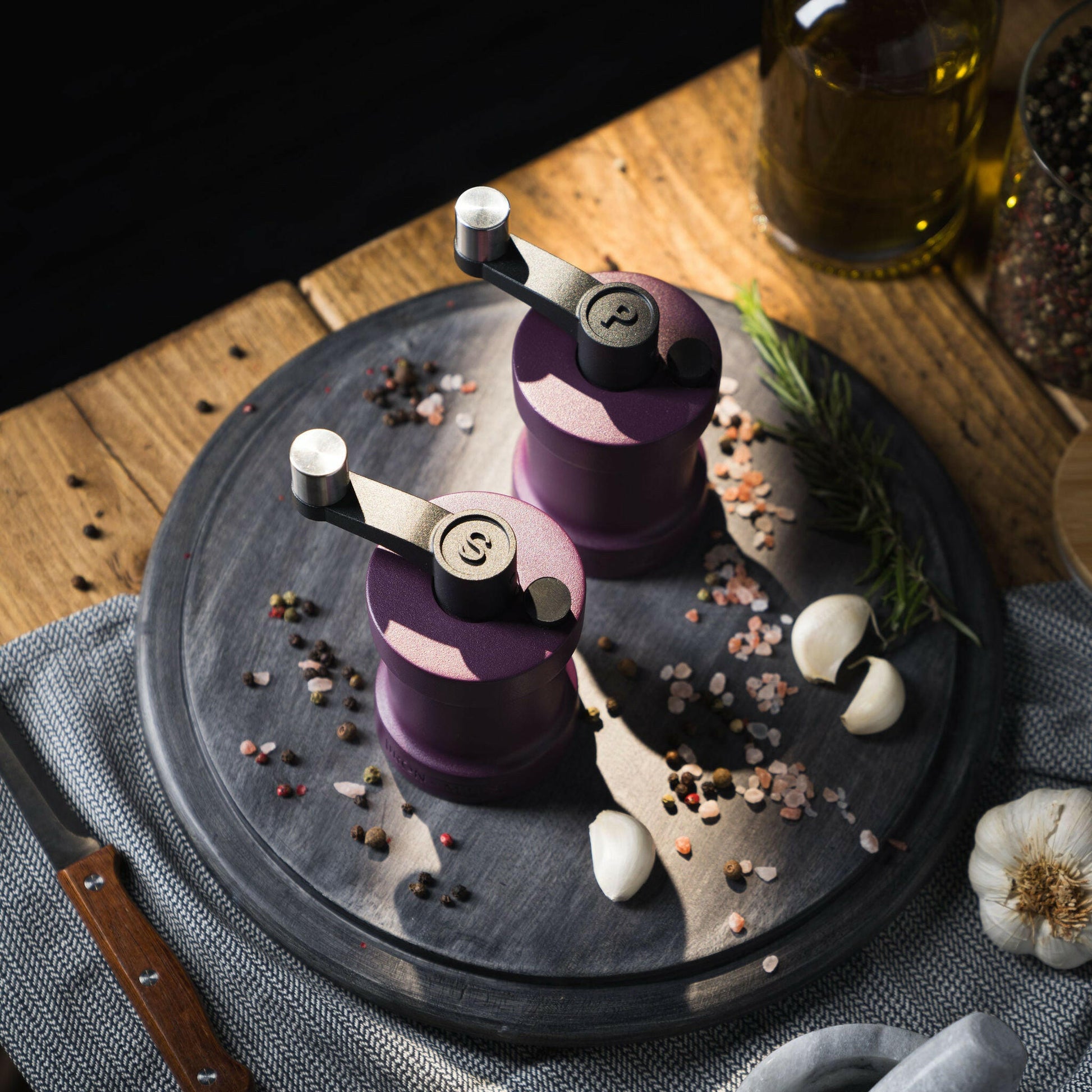 Iron-Mills purple salt and pepper mills on a chopping board in a luxurious kitchen with condiments nearby