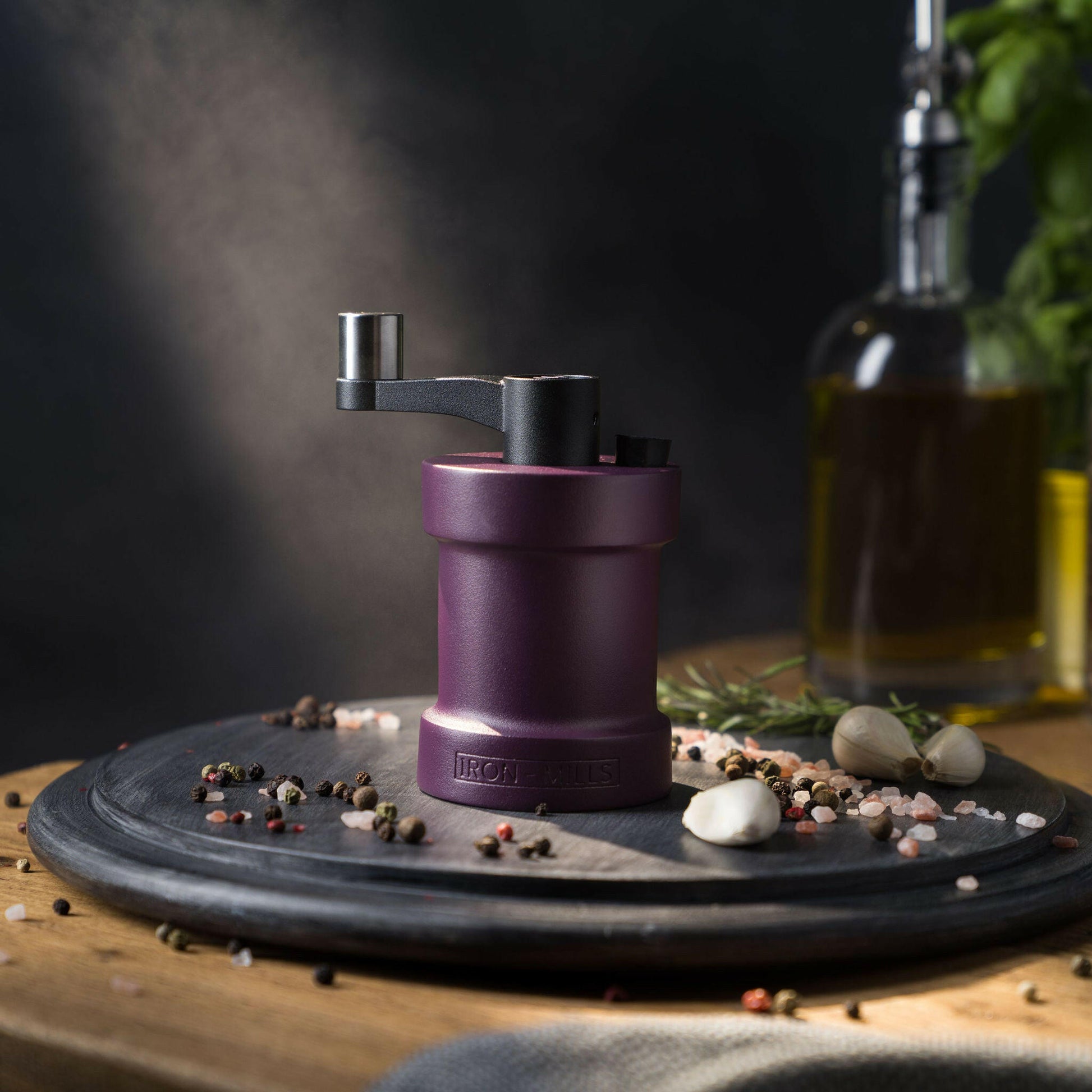 Iron-Mills purple salt mill on a chopping board in a regal kitchen with salt and peppercorns around