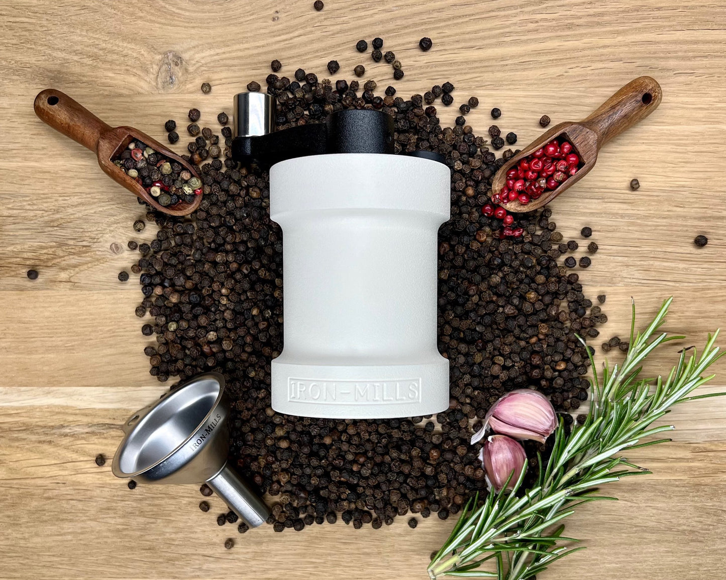 The Oyster White Pepper Mill By Iron-Mills on a Bed of Mixed Pepper Corns